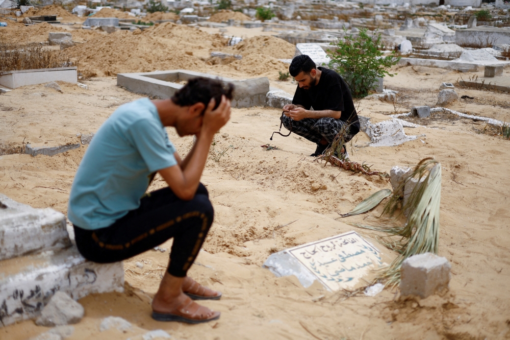 Uncle of Sabreen al Rouh crouches next to her grave in Rafah in the southern Gaza Strip