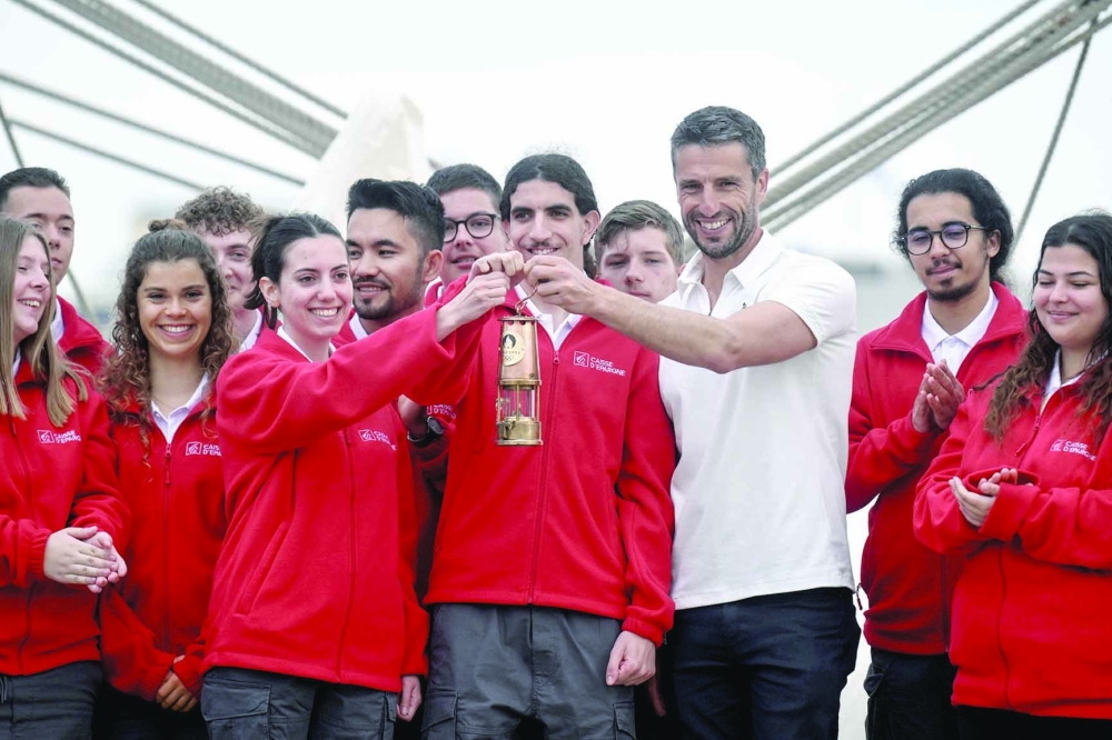 French President of the Paris 2024 Olympics and Paralympics Organising Committee (Cojo) Tony Estanguet carries the Olympic flame as he pose with young "eclaireur" sailors on board French 19th-century three-masted barque Belem to begin the flame's journey to France on April 27, 2024 AFP

