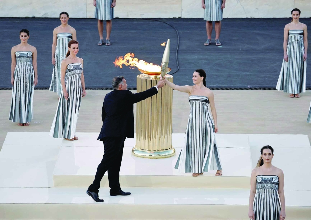 Greek actress Mary Mina, playing the role of High Priestess gives the torch to President of the Hellenic Olympic Committee and member of the International Olympic Committee -- REUTERS
