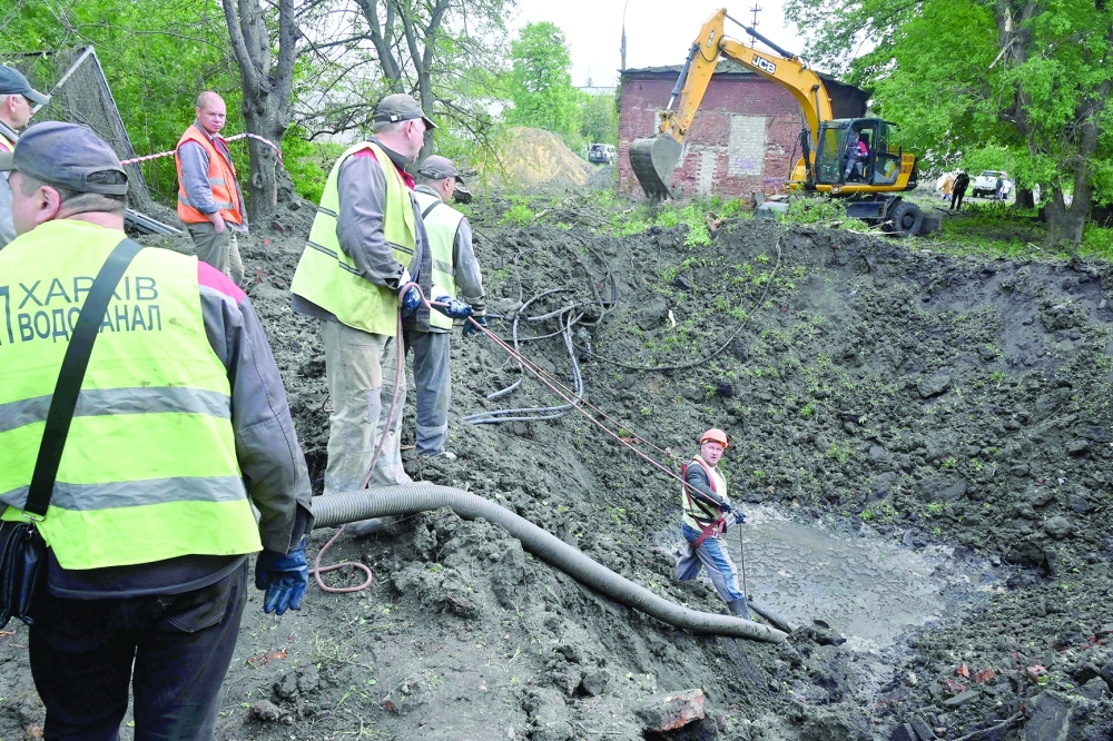 Utility workers operate next to a crater in the courtyard of a hospital in Kharkiv. — AFP 