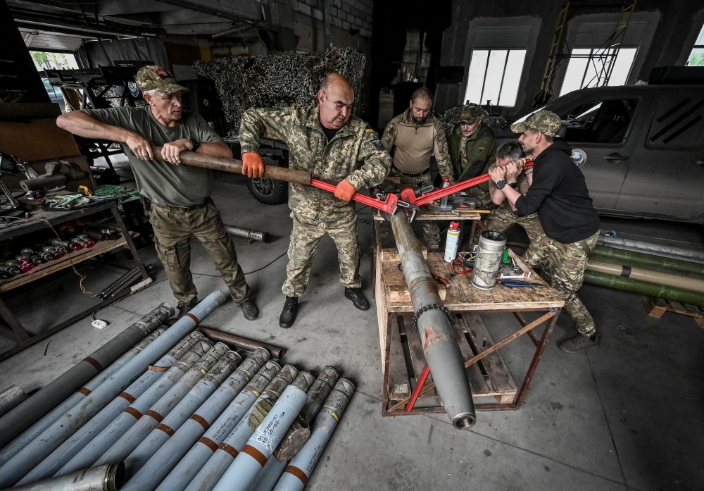 Members of the company tactical group "Steppe Wolves" disassemble a shell for a BM-21 Grad, in Zaporizhzhia region, Ukraine. — Reuters 