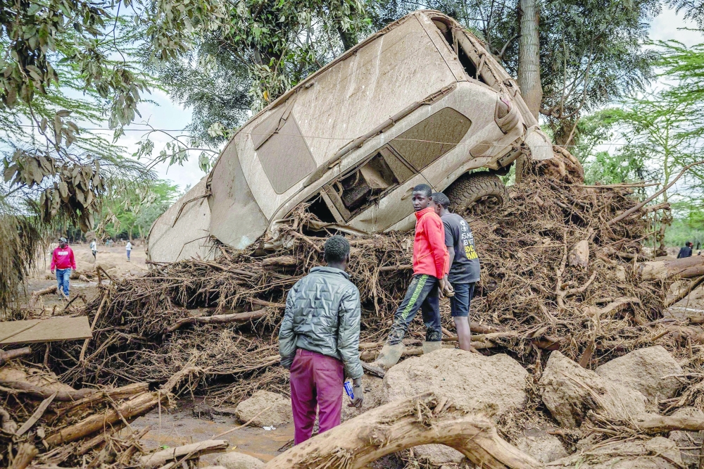 Young men inspect a destroyed car carried by waters in an area heavily affected by torrential rains and flash floods in the village of Kamuchiri. — AFP 