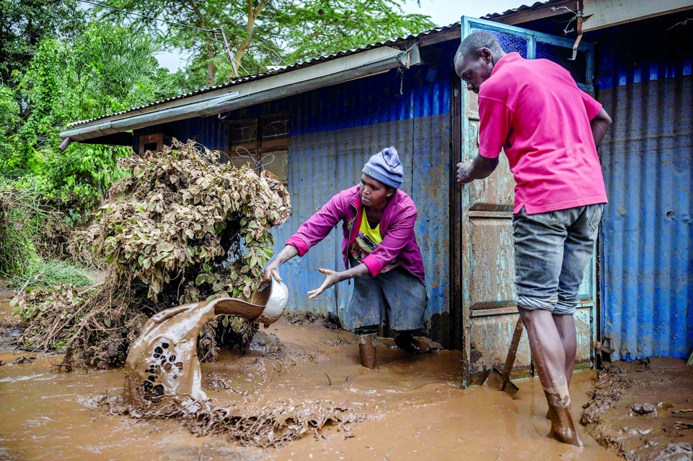 A woman and a man take mud and water out of their house in an area heavily affected by torrential rains and flash floods in Mai Mahiu. — AFP file photo