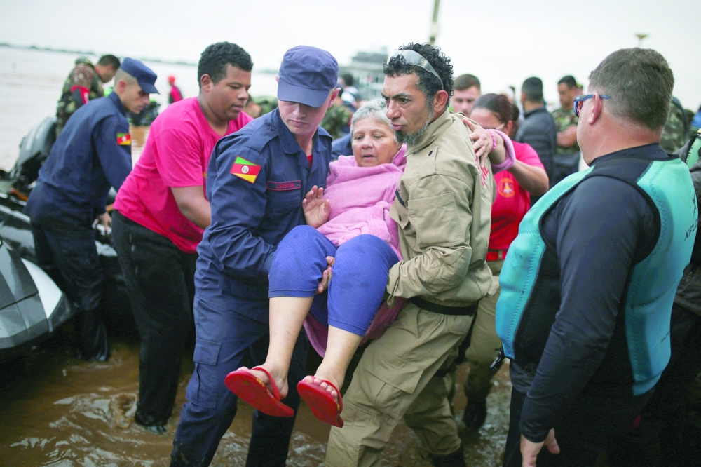 Rescue workers carry a woman after being rescued from the floods in Porto Alegre, Brazil. — Reuters 
