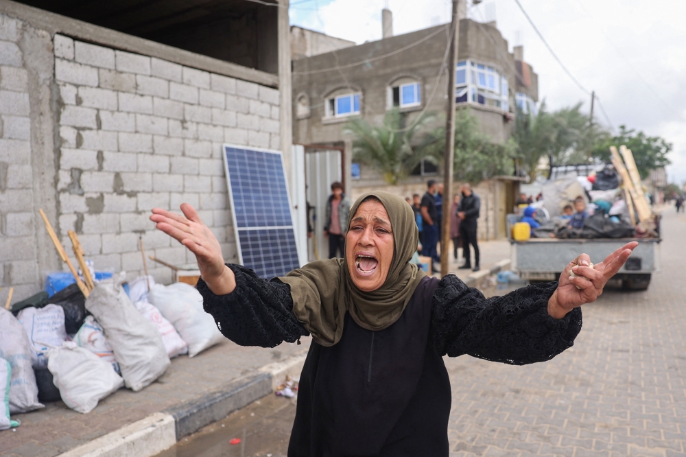 A woman reacts as displaced Palestinians in Rafah in the southern Gaza Strip pack their belongings following an evacuation order by the Israeli army on May 6, 2024
