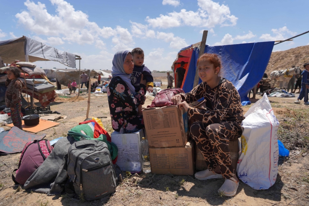 Displaced Palestinians arrive with their belongings on a beach, near Deir el-Balah, in the central Gaza Strip. — AFP 