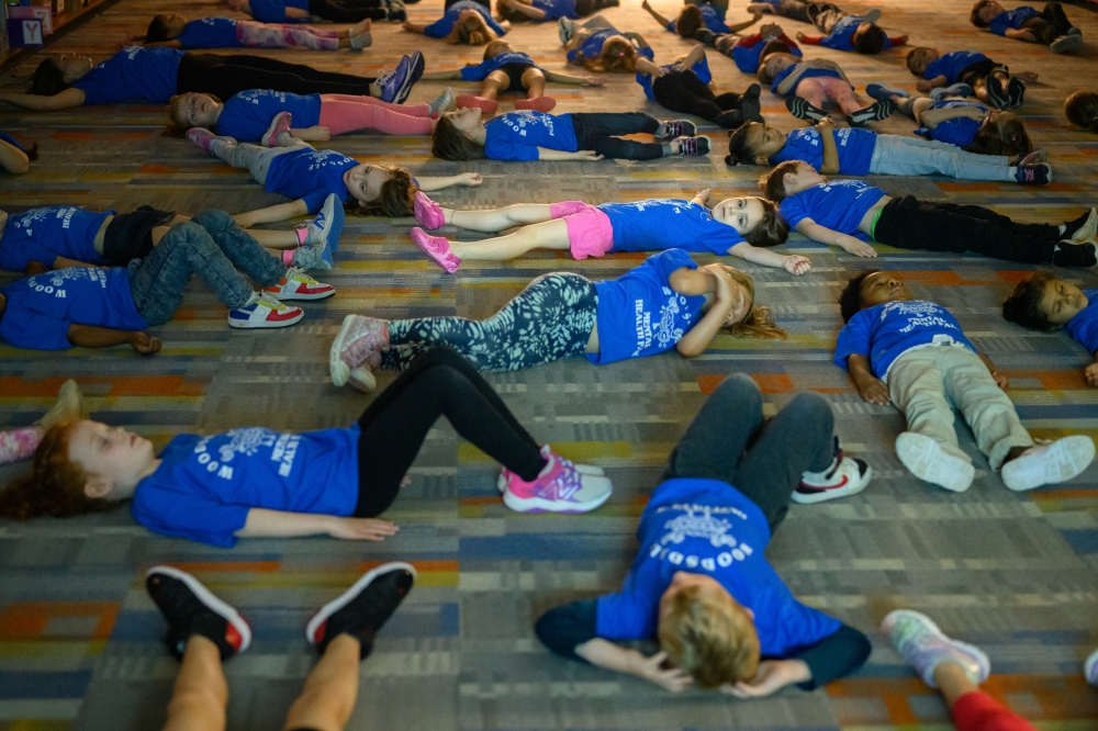 Students rest after yoga during a mental health fair at Woodsdale Elementary School in Wheeling, W.Va., April 19, 2024. (Rebecca Kiger/The New York Times)