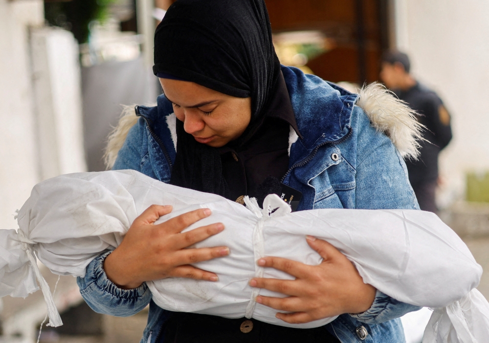 A woman cries while holding the body of a child killed in an Israeli strike at Abu Yousef al-Najjar hospital in Rafah on Monday. — Reuters