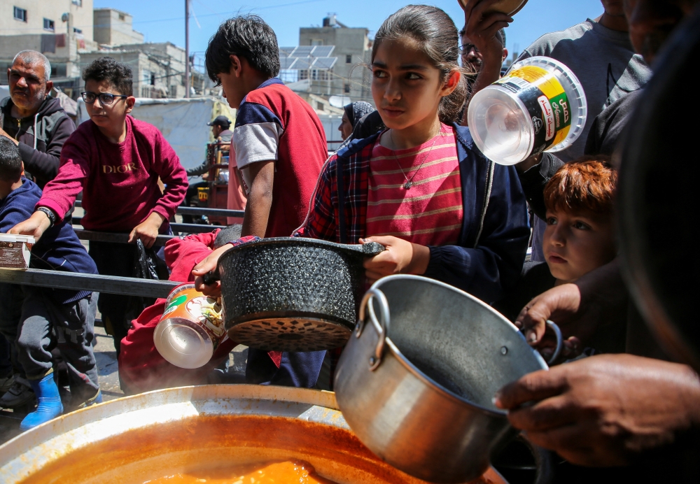 Palestinians gather to receive food cooked by a charity kitchen, amid shortages of aid supplies