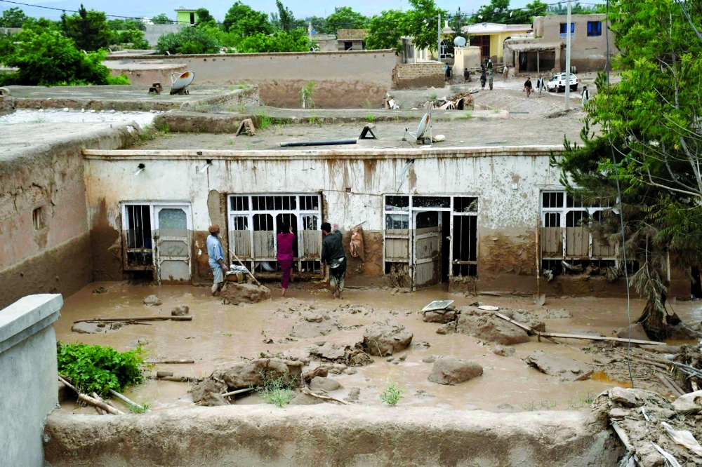 Afghan men clear mud from a house following flash floods after heavy rainfall at a village in Baghlan. — AFP