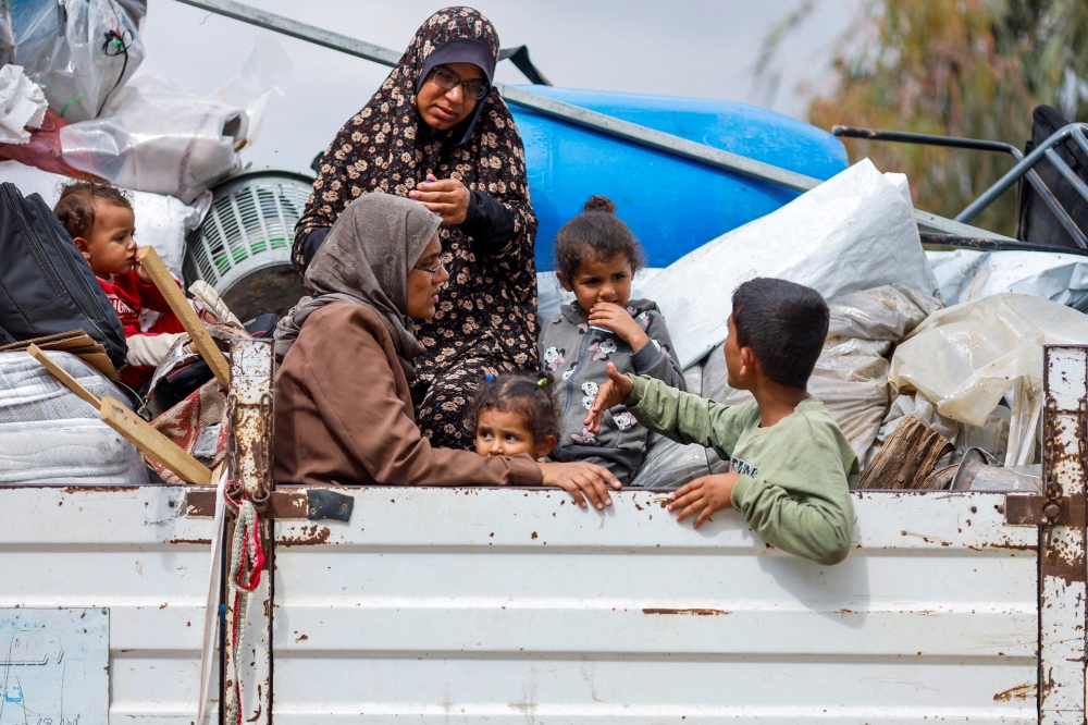 Palestinians ride on a vehicle as they flee Rafah after Israeli forces launched a ground and air operation. — Reuters 