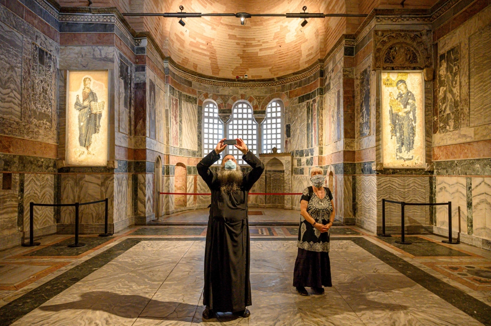 (FILES) A priest (L) and a woman visit the Chora or Kariye Museum, formally the Church of the Holy Saviour, a medieval Byzantine Greek Orthodox church, on August 21, 2020, in the Fatih district in Istanbul.  Turkish President Recep Tayyip Erdogan on August 21, 2020, ordered another ancient Orthodox church that became a mosque and then a popular Istanbul museum to be turned back into a place of Muslim worship. Erdogan on May 13, 2024, confirmed the reopening for Muslim worship of the Kariye mosque in Istanbul, converted from an ancient Byzantine Orthodox church. (Photo by BULENT KILIC / AFP)

