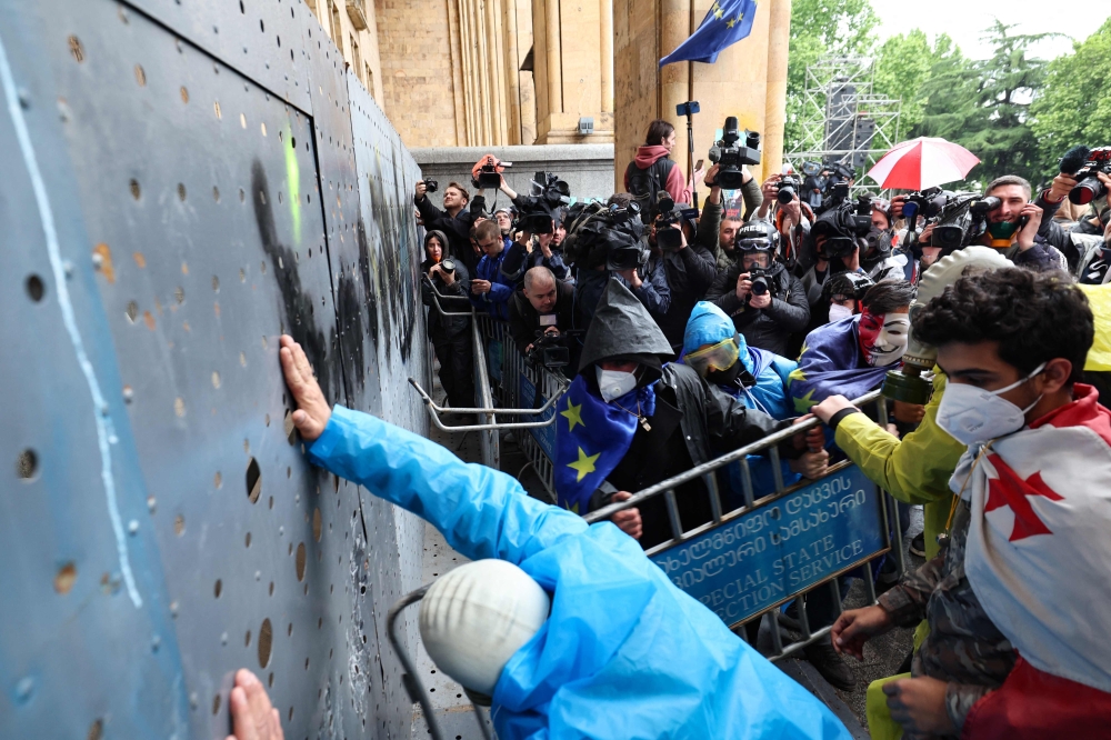 Georgian demonstrators attempt to break into the parliament through a metal barrier, in Tbilisi. — AFP 