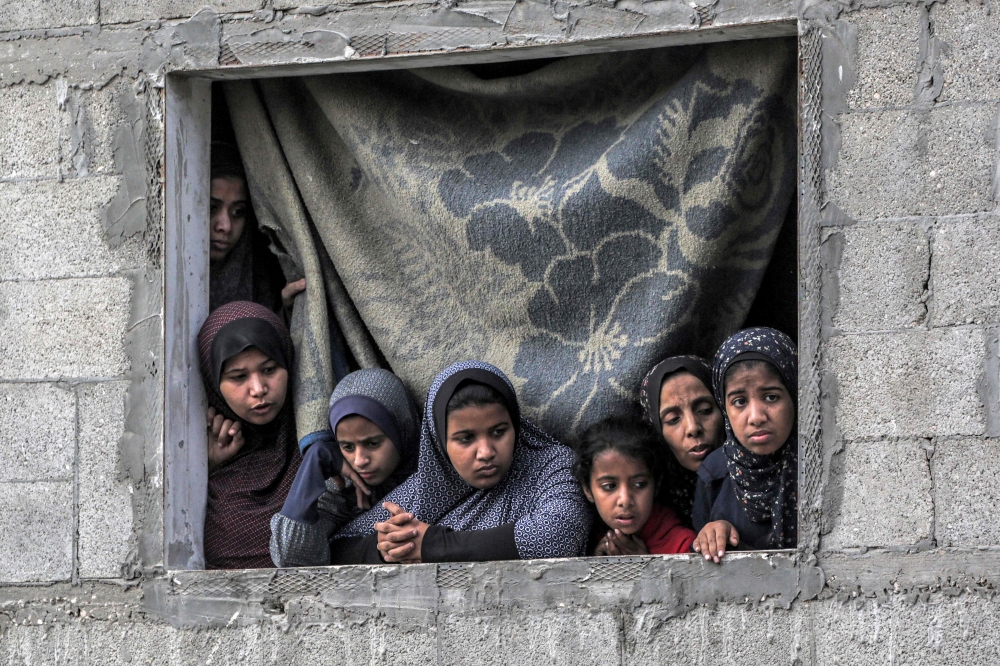 Girls look on from a window as they watch civil defence and volunteer efforts to recover survivors and bodies, aftermath of Israeli bombardment in Nuseirat. — AFP