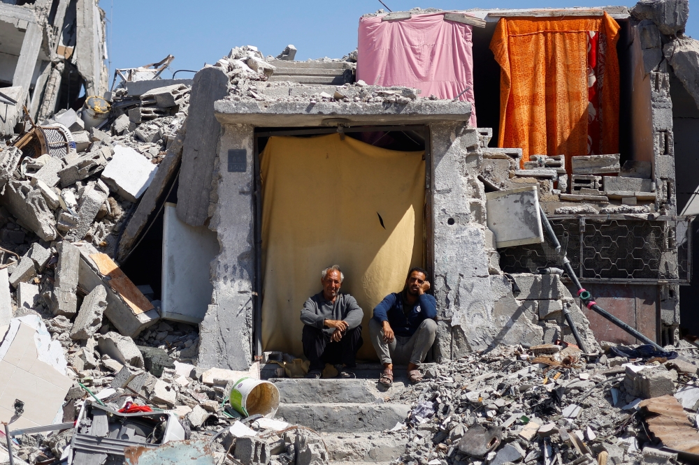 Palestinians sit at their house which was destroyed in an Israeli strike, in Khan Younis. — Reuters