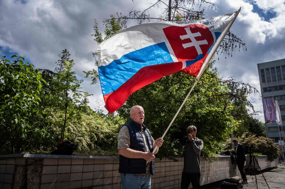 A man holding a Slovakia flag came to pray in front of the hospital in Banska Bystrica on Thursday. - AFP