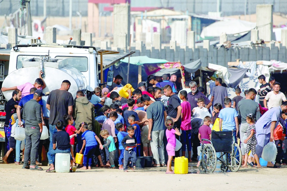 Displaced Palestinians queue to buy water from a water truck next to their temporary camp in Rafah. 