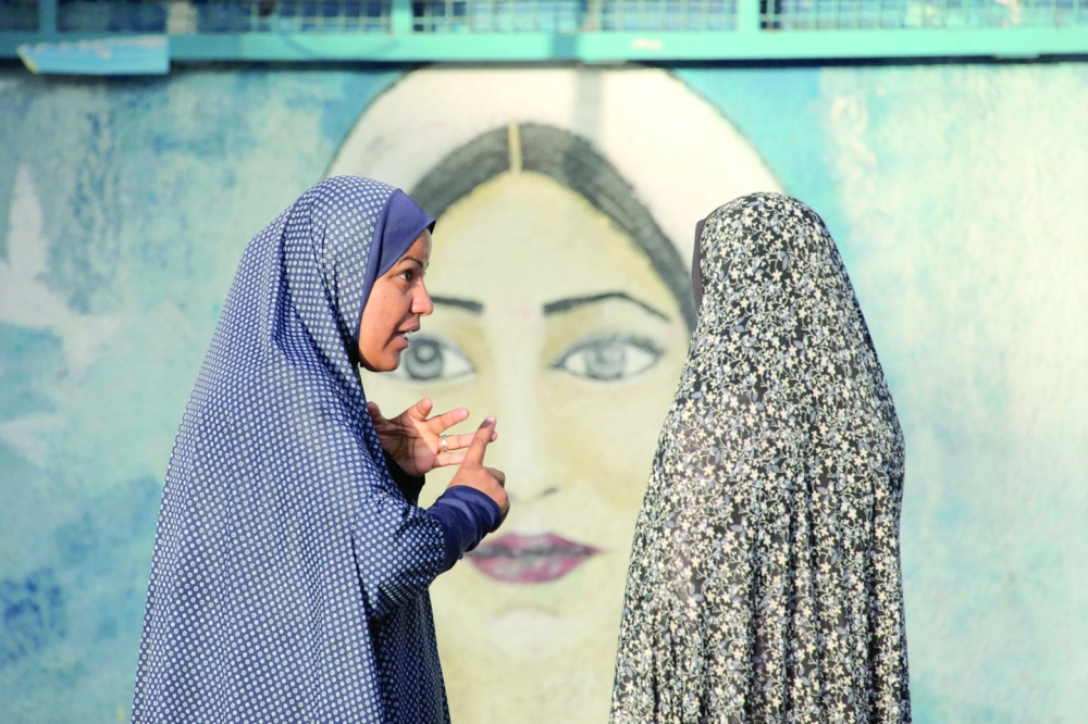 Displaced Palestinian women talk in the courtyard of an UNRWA school in which they are taking shelter in Nuseirat in the central Gaza Strip 