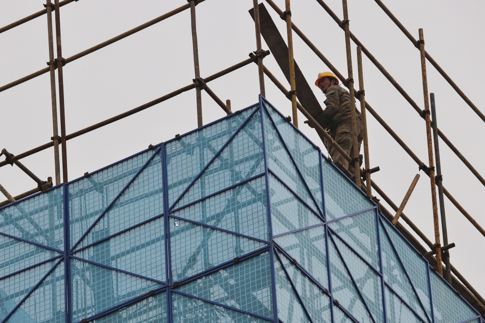 A man walks on a scaffolding at the construction site of the Beijing Xishan Palace apartment complex developed by Kaisa Group Holdings Ltd in Beijing. — Reuters