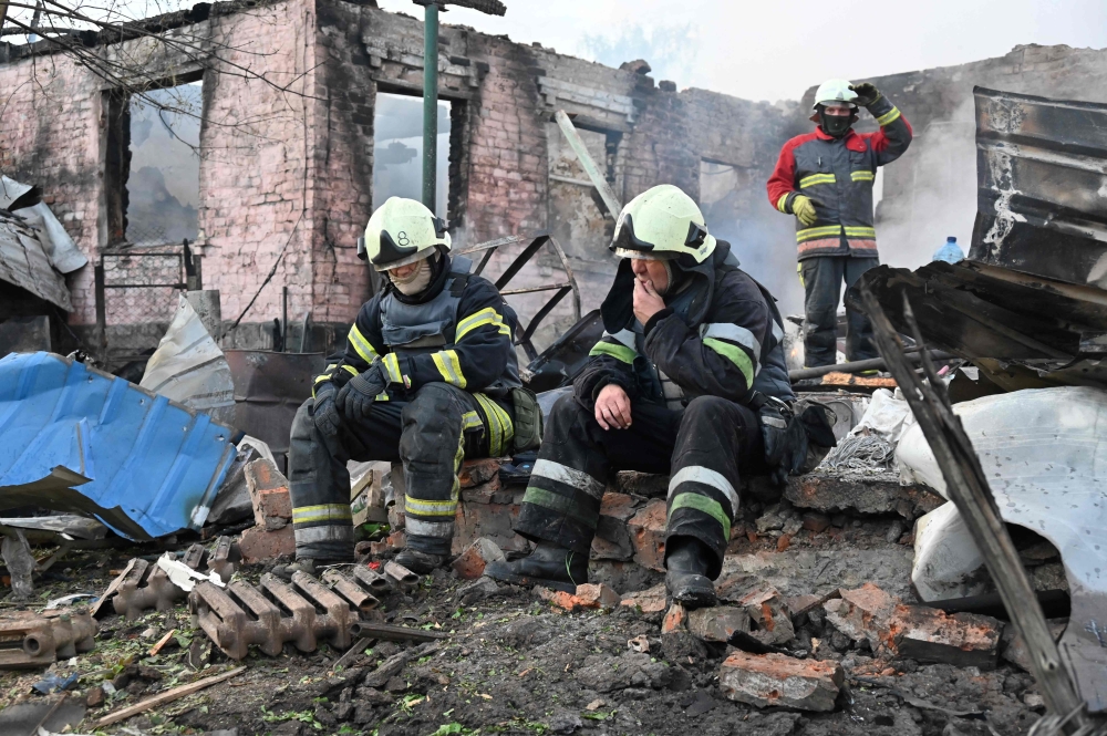 Firefighters rest after extinguishing a fire in a private house destroyed by a Russian drone attack in the suburbs of Kharkiv. — AFP 