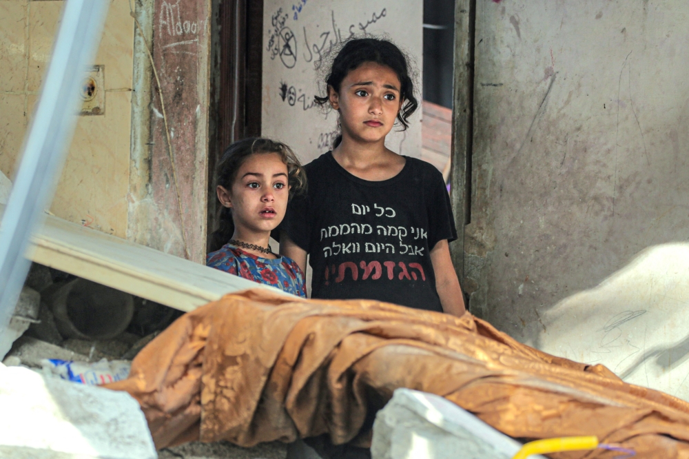 Palestinian children react as they check the damages in Nuseirat following Israeli bombardment overnight on May 23