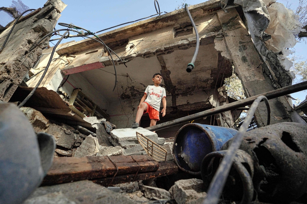 A boy stands on the rubble of a destroyed house in Nuseirat following Israeli bombardment on Thursday. — AFP