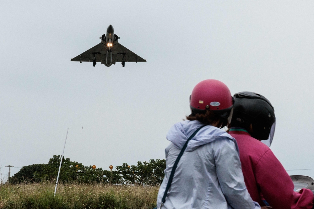 Two people ride a motorcycle as a Taiwanese Air Force Mirage 2000 fighter jet approaches for landing at an air force base in Hsinchu in northern Taiwan on Thursday. — AFP 