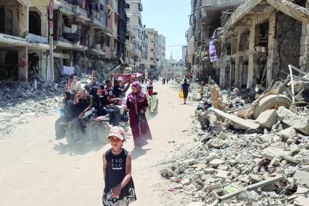 Displaced Palestinians ride in the back of a vehicle along a devastated street in Khan Yunis.