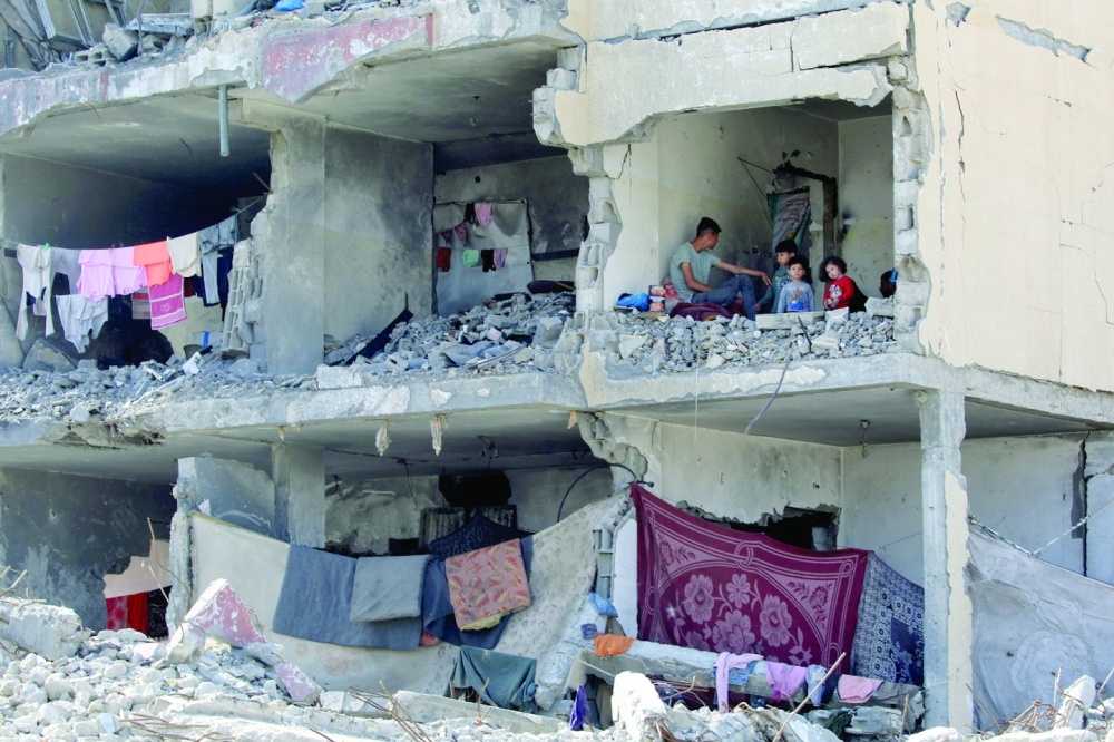 A Palestinian man and his children sit in a destroyed room following the targeting or a residential building by an Israeli airstrike in Rafah on Friday.