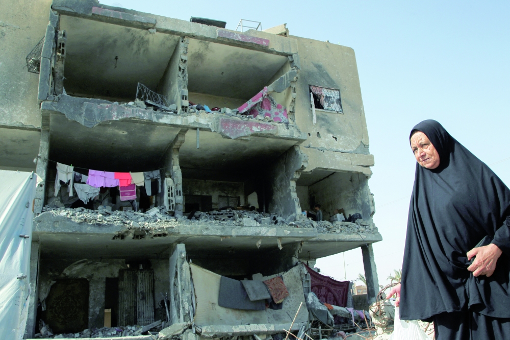A Palestinian woman walks past a house destroyed by an Israeli strike in Rafah on Friday. 