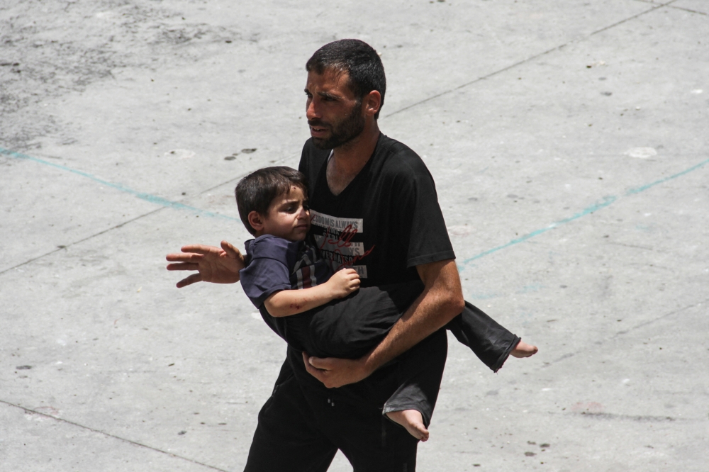 A man carries a child amid the ongoing conflict in Gaza on Saturday. - Reuters