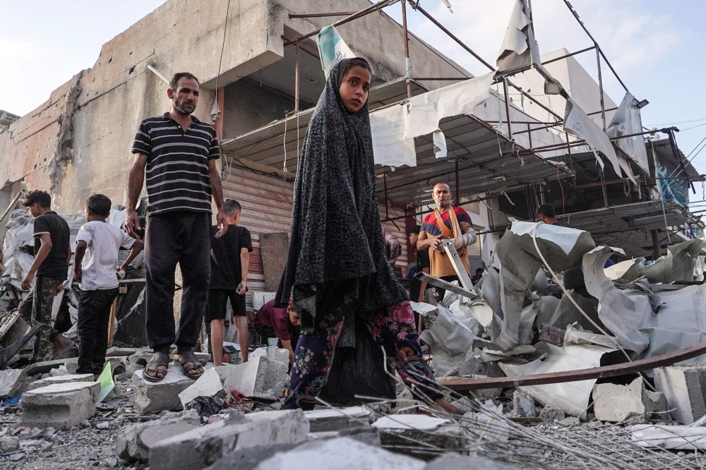 Palestinians inspect the aftermath of an Israeli strike on a building in Nuseirat. — AFP 