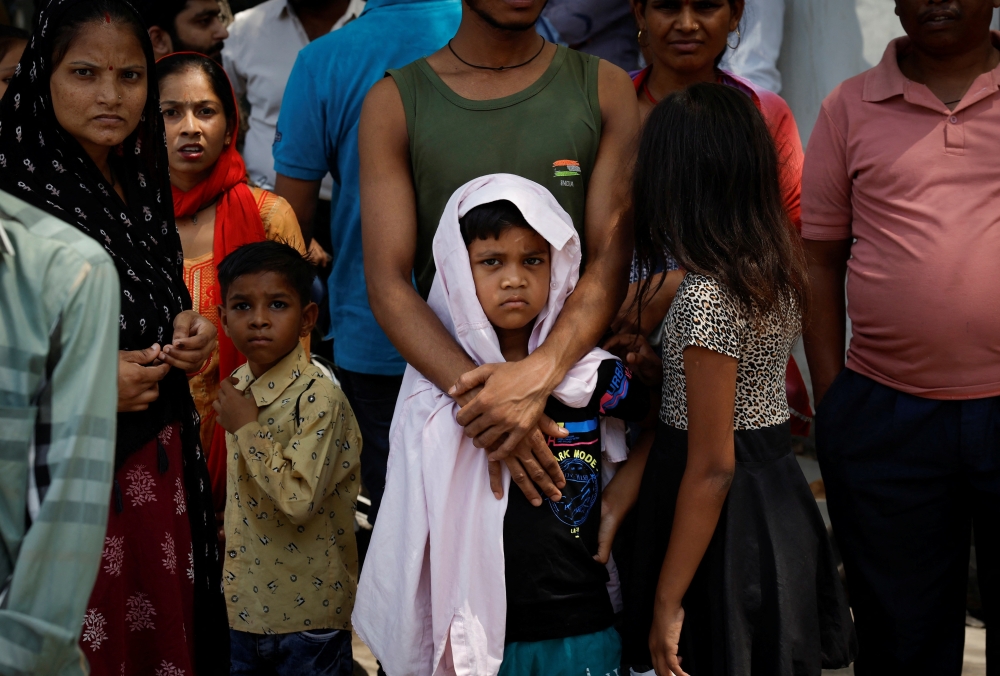 People stand outside a baby care hospital where several newborns died in a fire