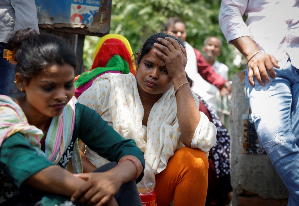 Relatives of a newborn sit outside a baby care hospital where several newborns died in a fire