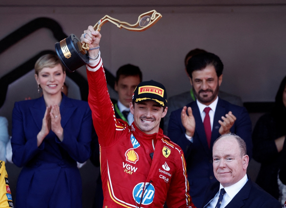 Formula One F1 - Monaco Grand Prix - Circuit de Monaco, Monaco - May 26, 2024 Ferrari's Charles Leclerc celebrates on the podium with a trophy after winning the Monaco Grand Prix alongside Prince Albert II of Monaco REUTERS/Benoit Tessier     TPX IMAGES OF THE DAY
