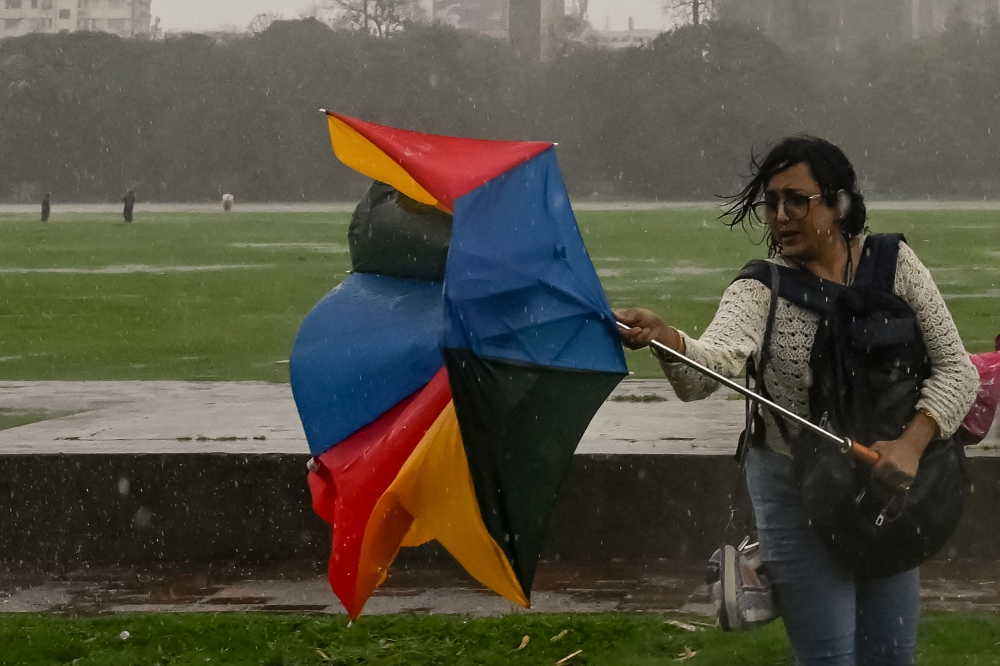 A gust of wind flips an umbrella of a visitor in Maidan, a vast urban green space, during a rainfall in Kolkata on May 27