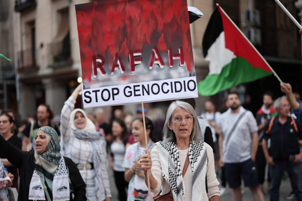 A protestor holds a sign reading "Rafah, Stop genocide" during a pro-Palestinian demonstration, in Madrid. — AFP 