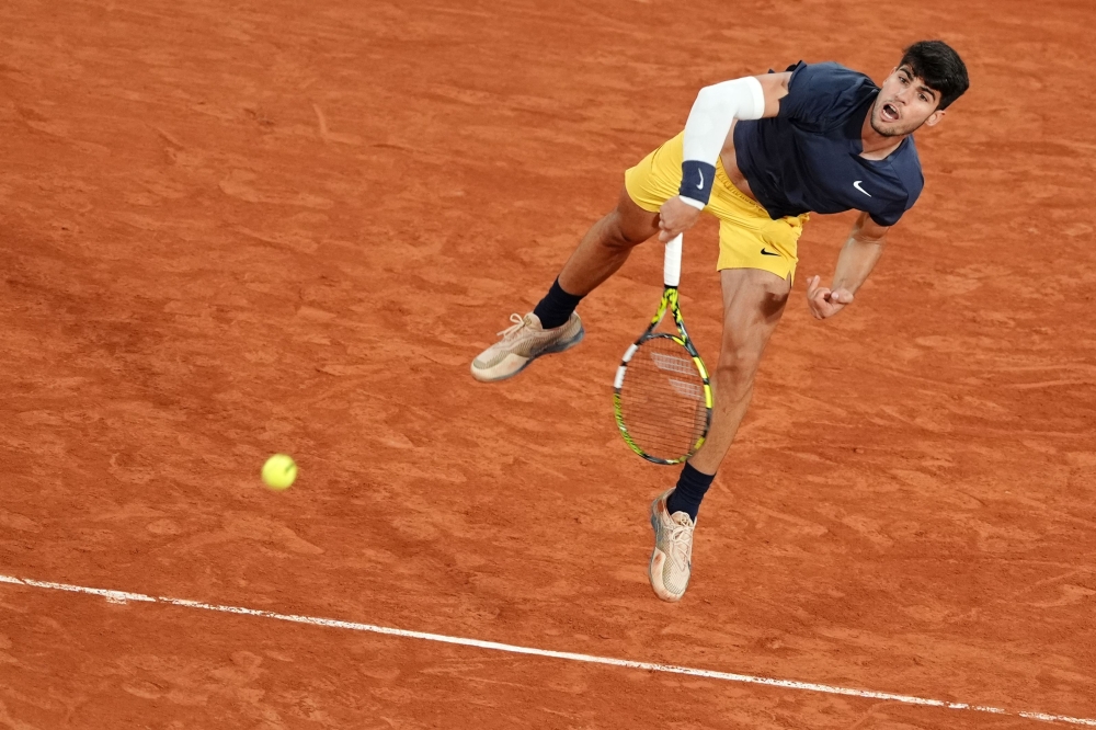 TOPSHOT - Spain's Carlos Alcaraz Garfia serves to Dutch Jesper De Jong during their men's singles match on Court Philippe-Chatrier on day four of the French Open tennis tournament at the Roland Garros Complex in Paris on May 29, 2024.  (Photo by Dimitar DILKOFF / AFP)

