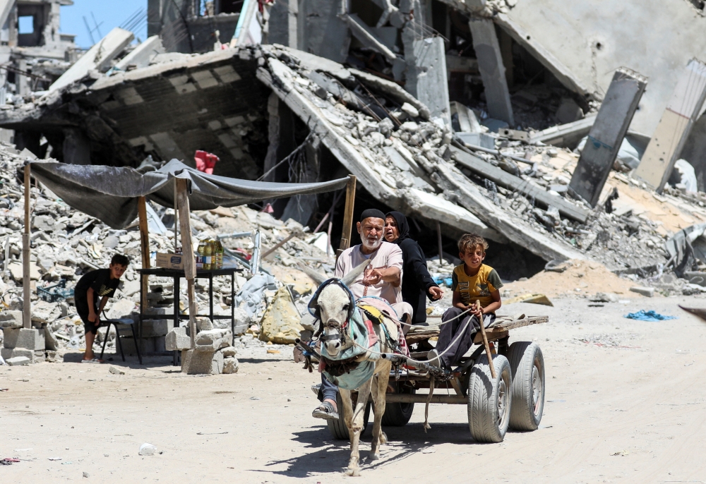 Palestinians use a donkey-drawn cart, near houses destroyed in the Israeli military offensive, in Khan Younis on Thursday