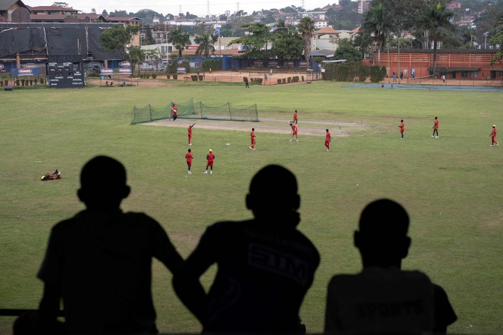 Young Ugandan cricket players watch from the stands 