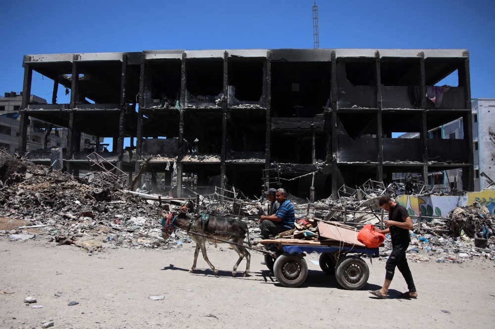 TOPSHOT - Palestinians transport some salvaged belongings as they leave the Jabalia refugee camp in the northern Gaza Strip after they returned briefly to check on their homes on May 31, 2024, amid the ongoing conflict between Israel and the militant group Hamas.  (Photo by Omar AL-QATTAA / AFP)

