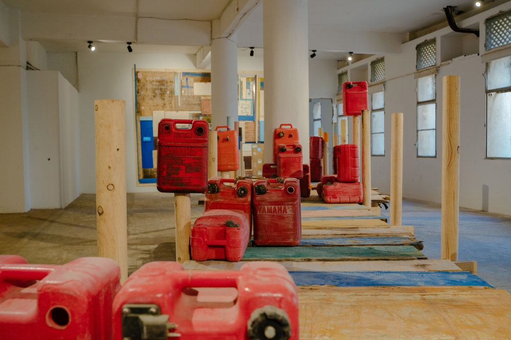 An installation includes a pontoon made from fragments of wood recovered from the coastline by the artist Hamedine Kane, and red gas cans used for boats, at the Selebe Yoon art gallery during the OFF events in Dakar, Senegal, on May 17, 2024. (Carmen Abd Ali/The New York Times)