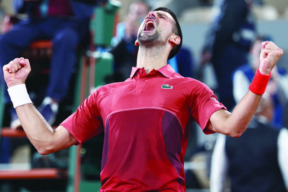 Novak Djokovic celebrates after winning against Italy's Lorenzo Musetti with a timer reading 4 hours and 28 minutes at the end of their men's singles match on Court Philippe-Chatrier on day seven of the French Open tennis tournament at the Roland Garros Complex in Paris on June 2, 2024.  (Photo by EMMANUEL DUNAND / AFP)