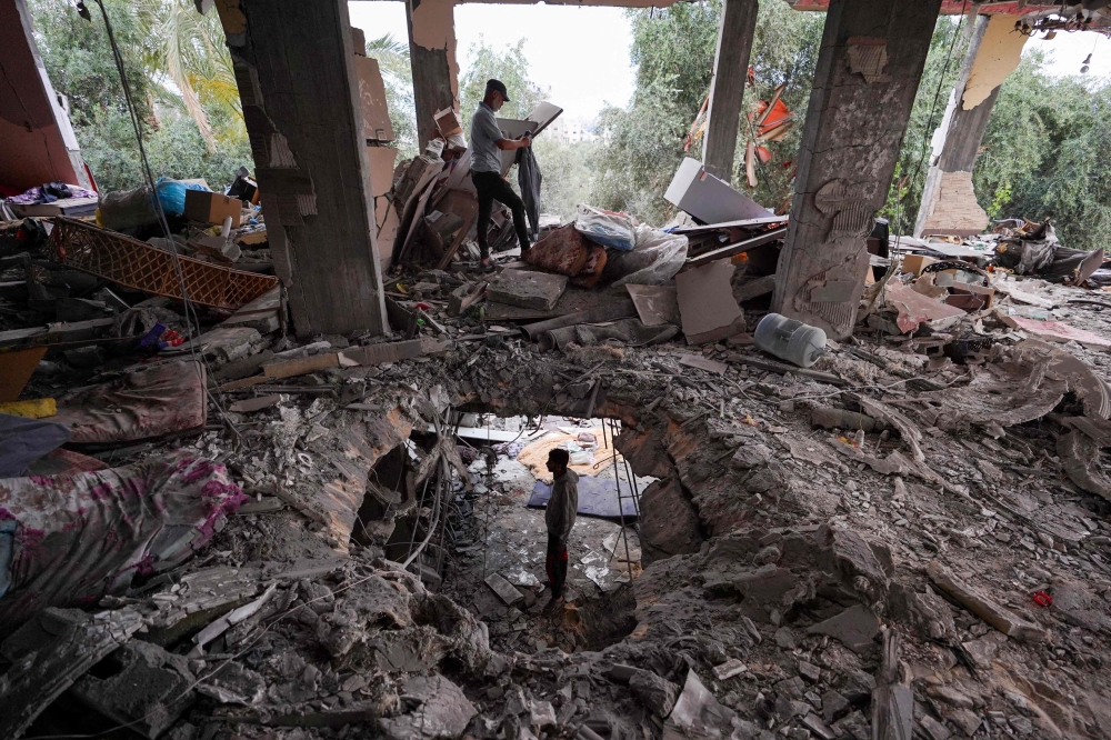 Palestinians inspect the damage to a house after it was hit in an Israeli strike in al-Bureij camp. — AFP 