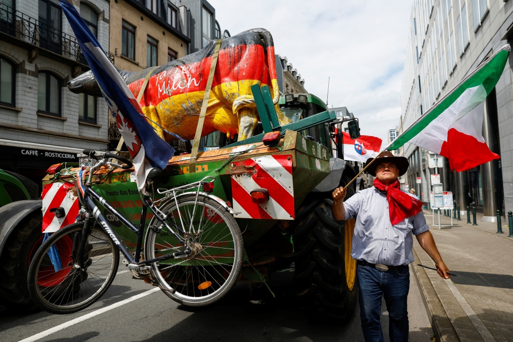 A man holds a flag as European farmers demonstrate ahead of European Parliament election in Brussels. 