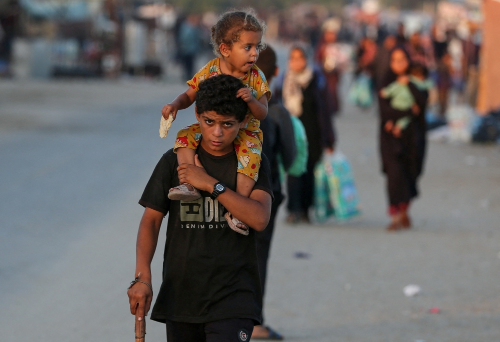 A Palestinian carries a child on his shoulders as they flee Rafah on Friday. 