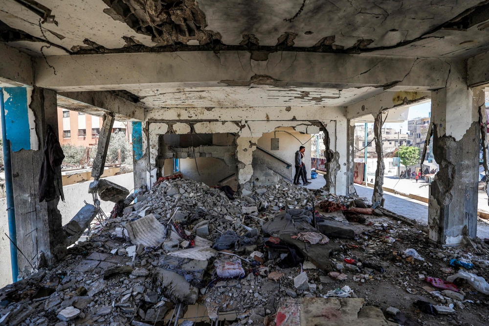 Boys walk past a destroyed classroom where people were sheltering at a school run by the UN Relief and Works Agency for Palestine Refugees (UNRWA)