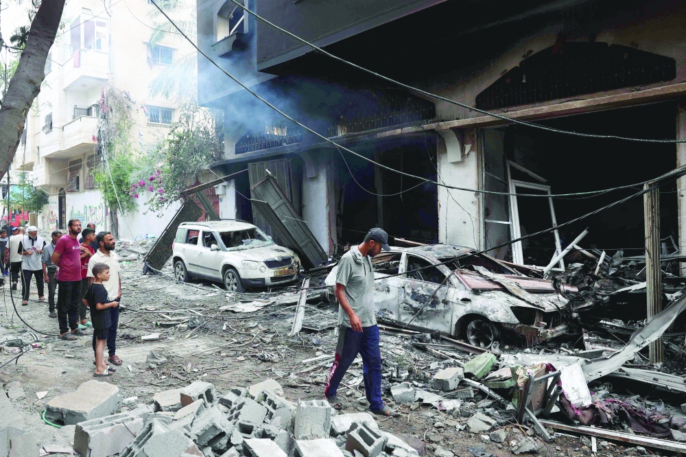 Palestinians inspect the damage and debris a day after an Israeli raid in the Nuseirat camp. — AFP