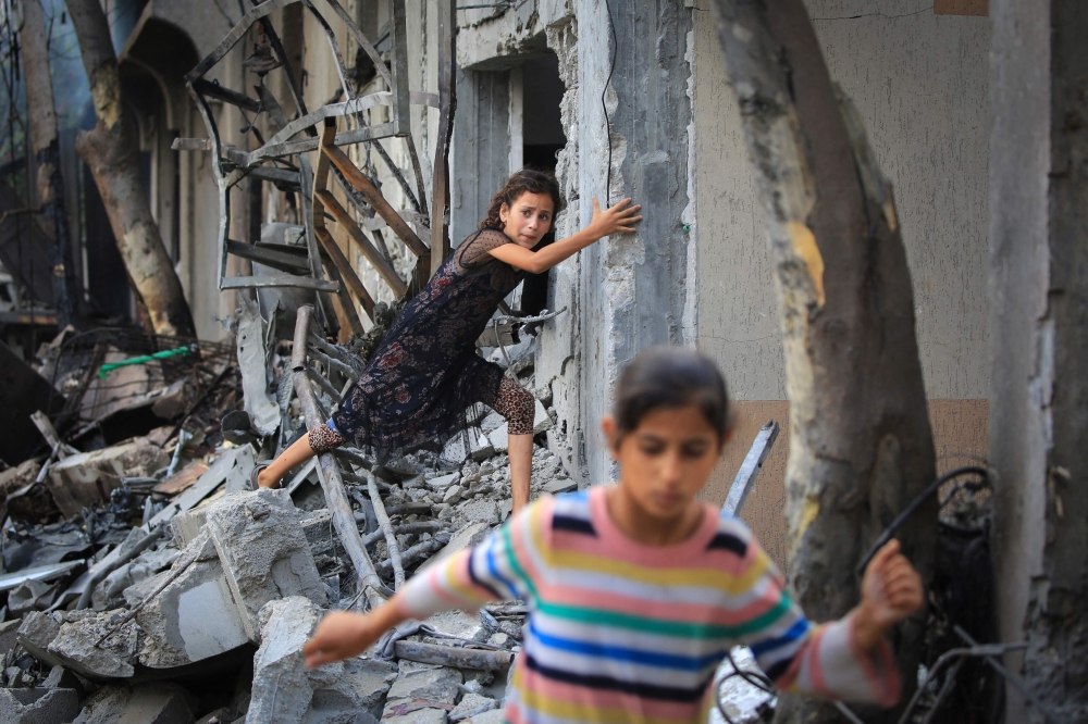 A Palestinian girl climbs over debris a day after an operation by the Israeli Special Forces in the Nuseirat camp