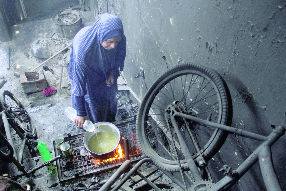 A displaced Palestinian woman uses water as she cooks as Gazan families struggle with water pollution and scarcity, in Jabalia refugee camp. — Reuters 